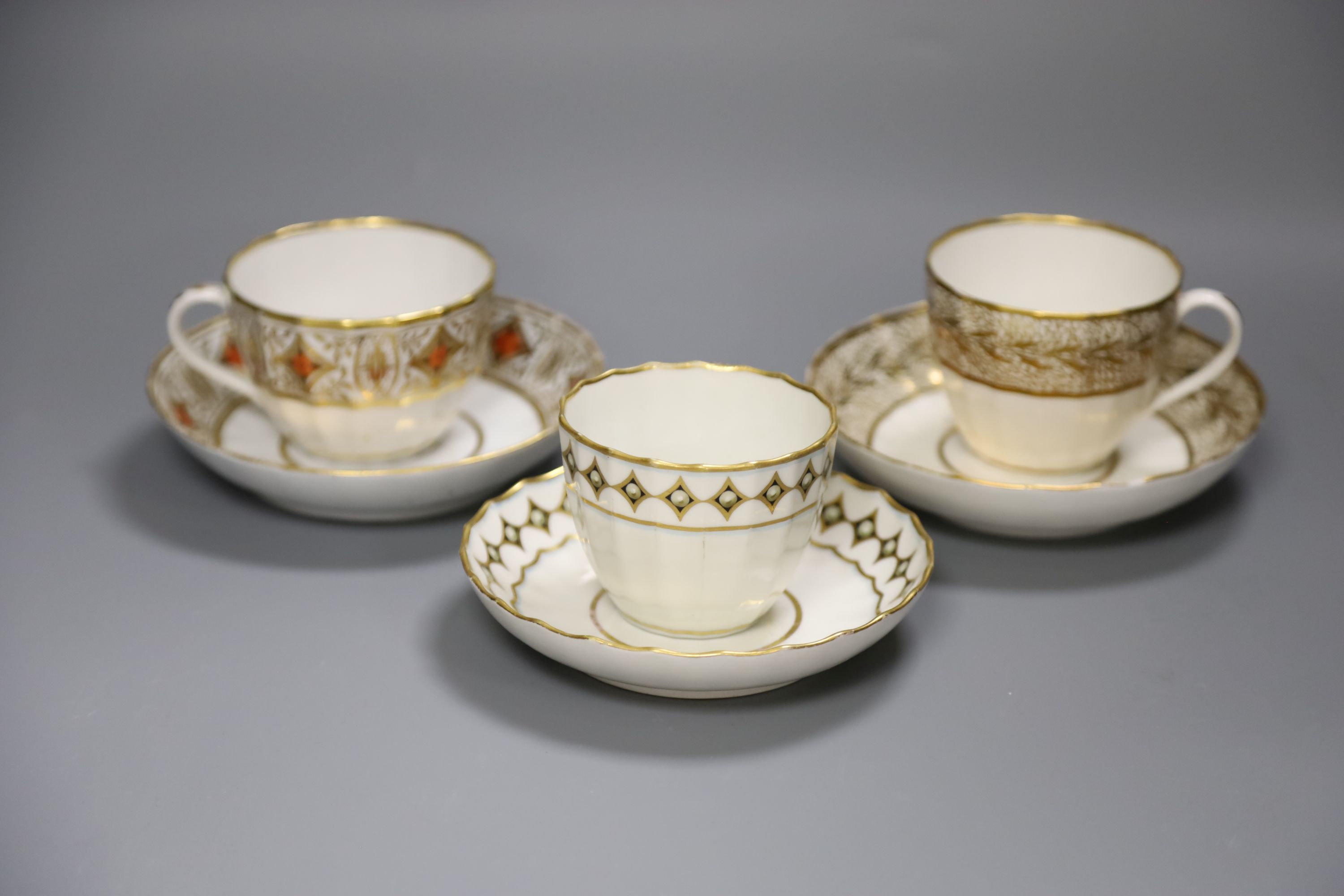 A Derby faceted teacup and saucer painted with pearls on diamond gilding pattern 135 in puce, another similar shaped Derby teacup